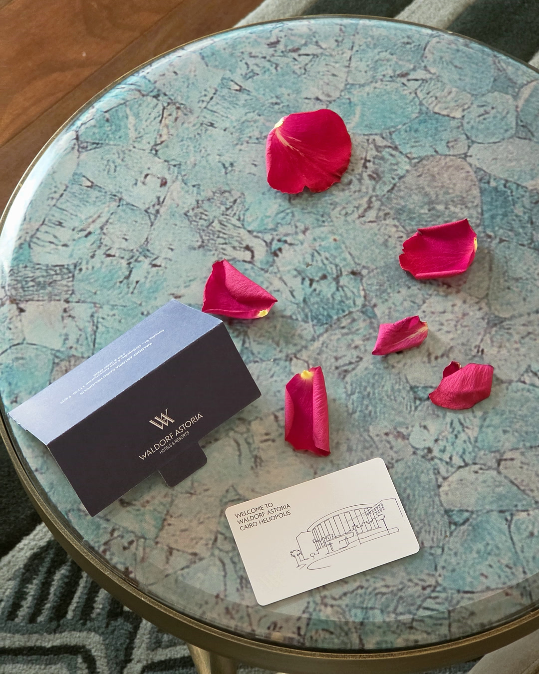 Rose petals and the welcome card on a stone side table
